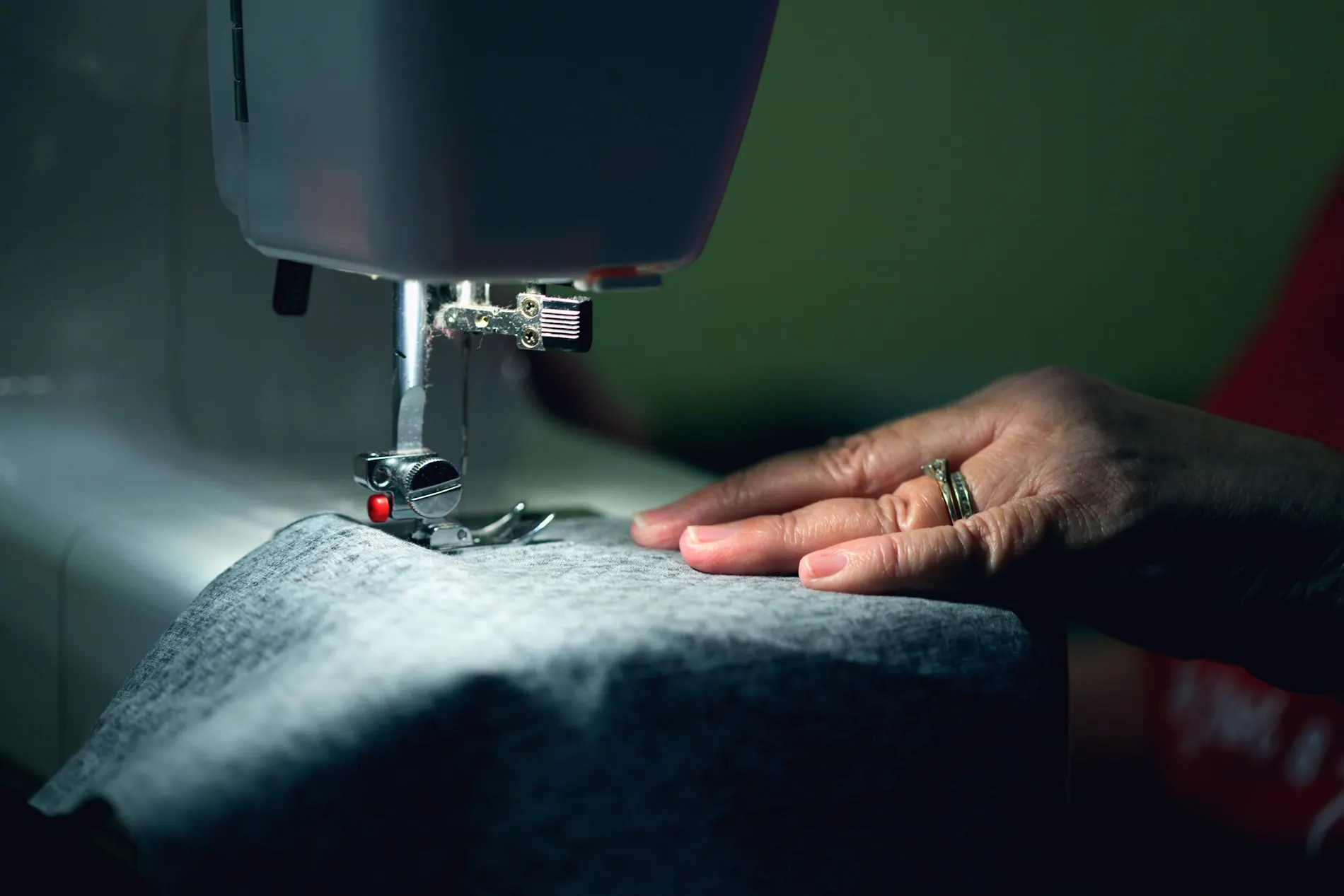 Manos cosiendo una tela técnica en una máquina de coser